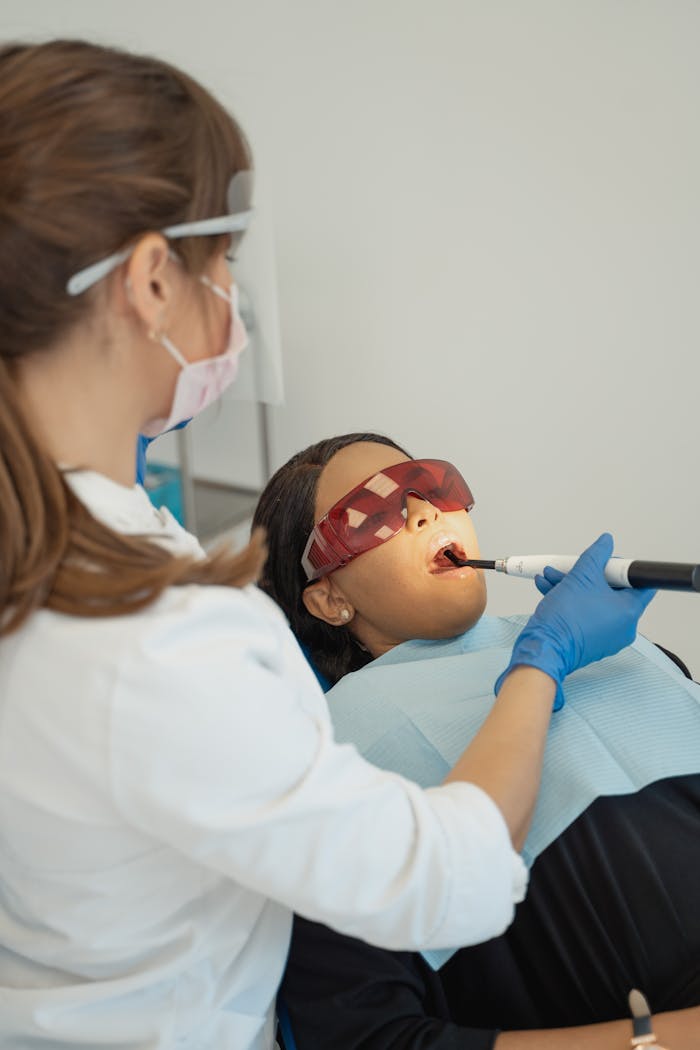A dentist uses a curing light on a patient in a modern clinic. Professional dental care in progress.